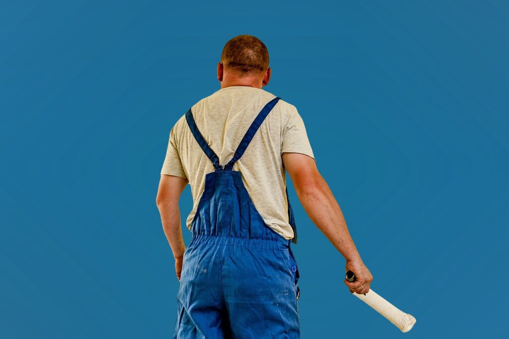 Schilder brengt verflaag aan op een muur met een roller